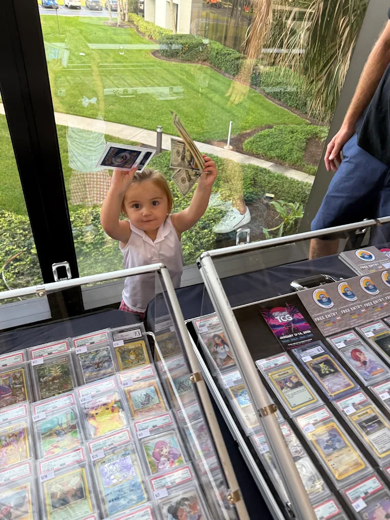 A kid holding up a card and cash after a trade at the ERA Cards table