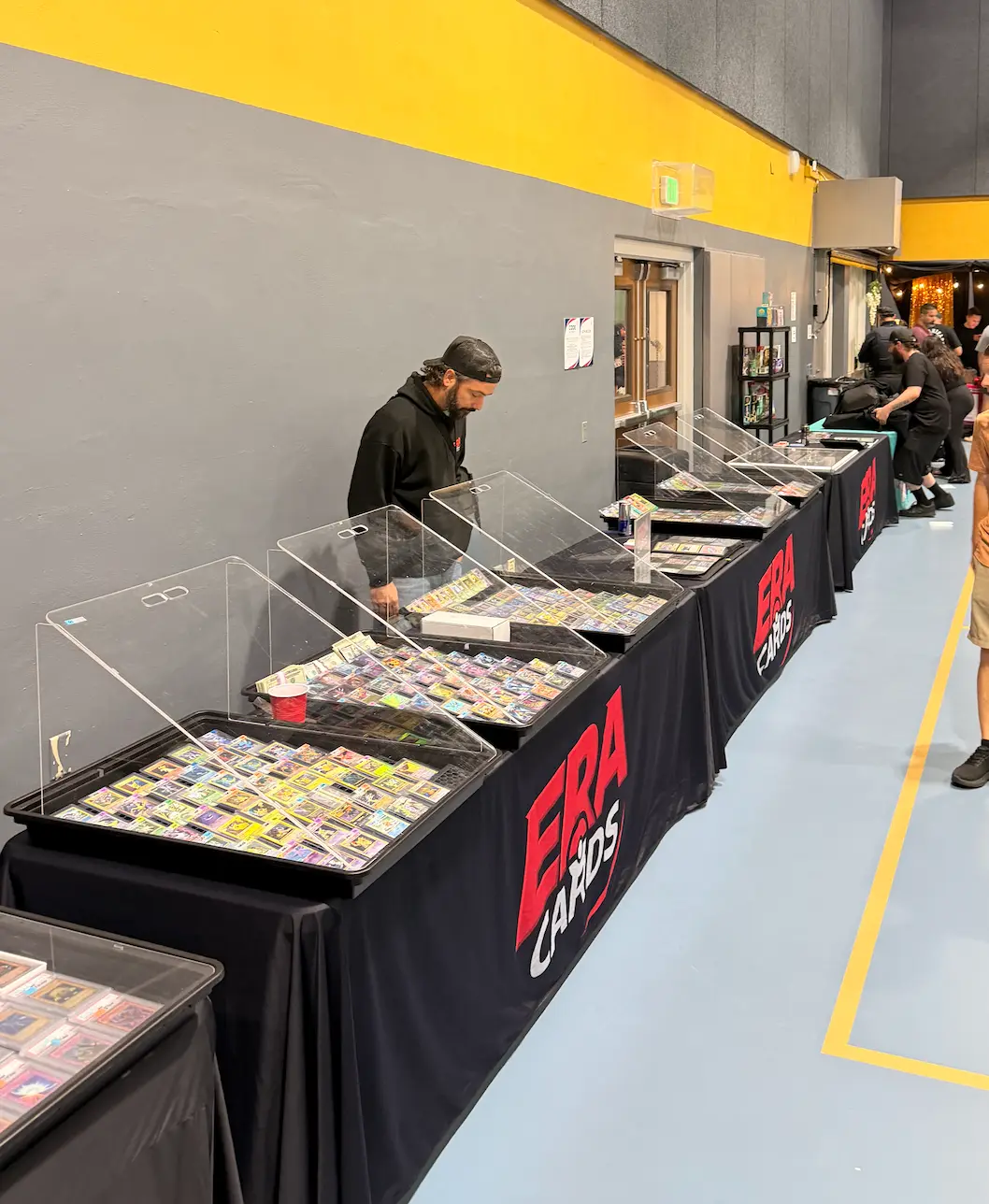 A long row of raw card trays under acrylic covers at the ERA Cards table